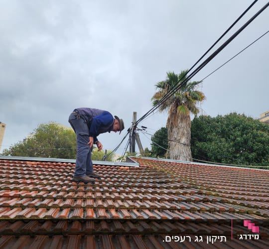 אדם עומד על גג רעפים אדום ובודק אותו